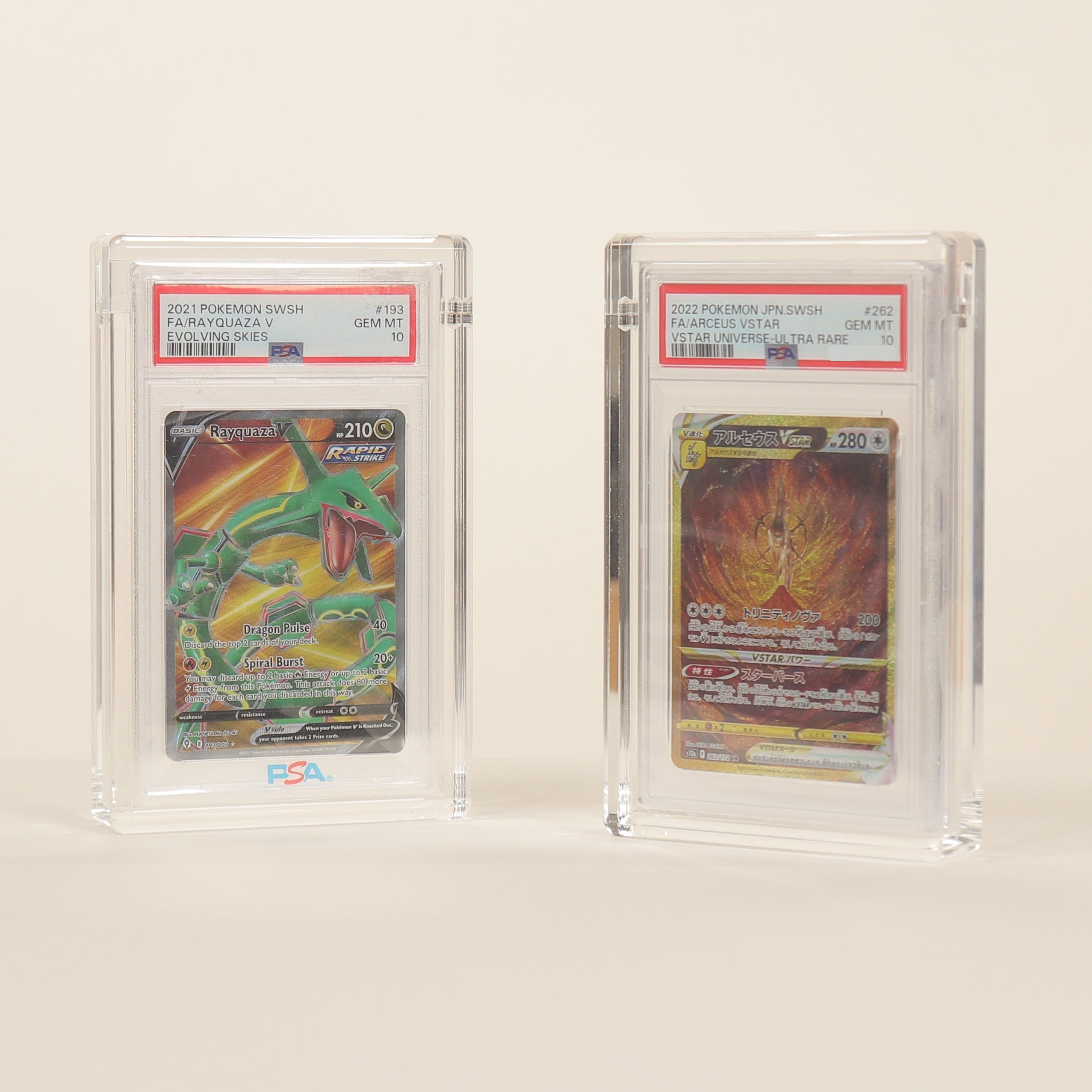 Two trading cards in acrylic protective cases on a beige background