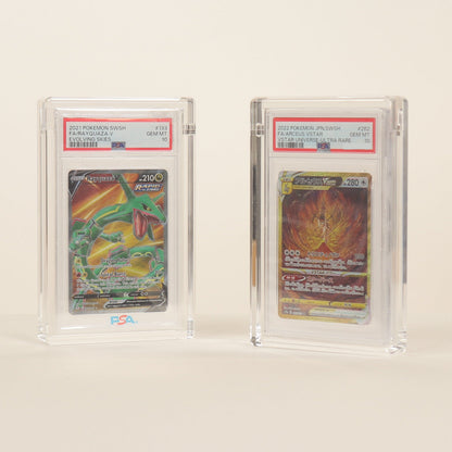Two trading cards in acrylic protective cases on a beige background